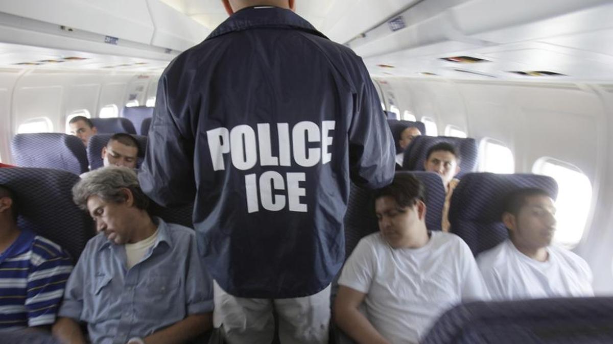 Federal agent walks among shackled Mexican immigrants being deported in 2010.