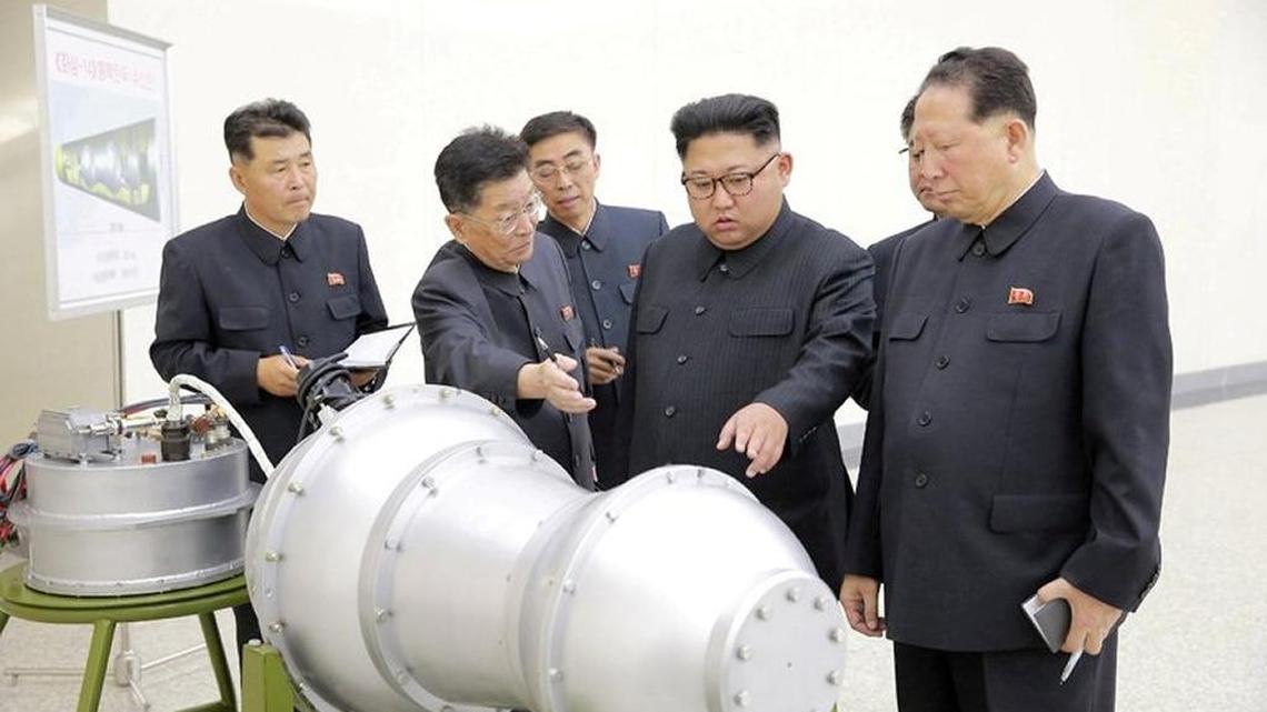 North Korean leader, Kim Jong-un, with two scientists examing rockets parts.