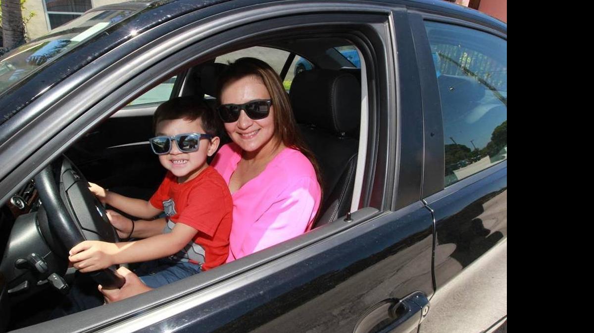 
Carolina Arguello, 38, and her 2-year-old son Andre Sarmiento sit in the 2011 BMW she uses as a driver-operator for Uber
