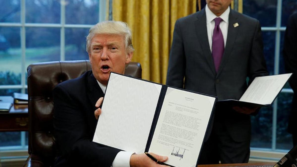 President Donald Trump holds up the executive order on Monday withdrawing the U.S. from the Trans Pacific Partnership.