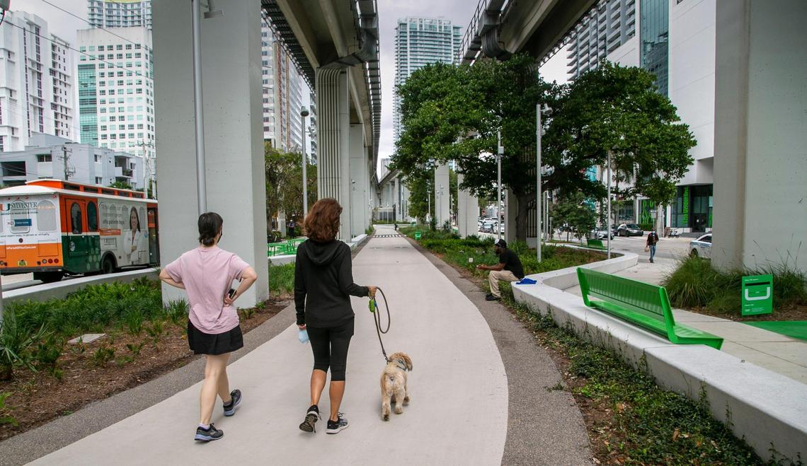 Two women walk a dog along the newly opened Brickell Backyard section of The Underline. The half-mile segment of the planned 10-mile linear park and trail under the elevated Metrorail tracks is the first to be finished.