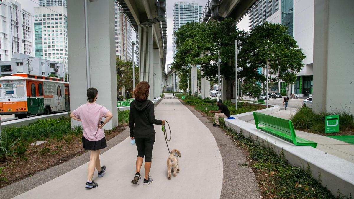 Two women walk a dog along the newly opened Brickell Backyard section of The Underline. The half-mile segment of the planned 10-mile linear park and trail under the elevated Metrorail tracks is the first to be finished.