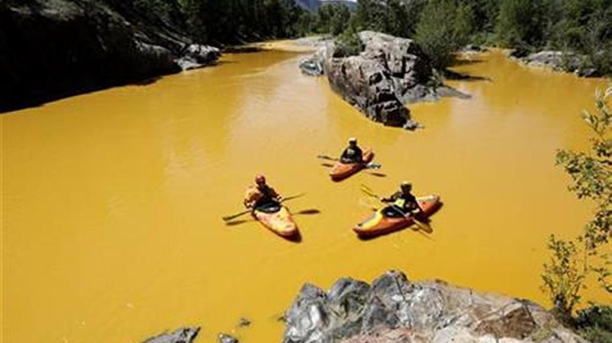 
In water colored yellow from a mine waste spill, officials examine the damage from kayaks.


