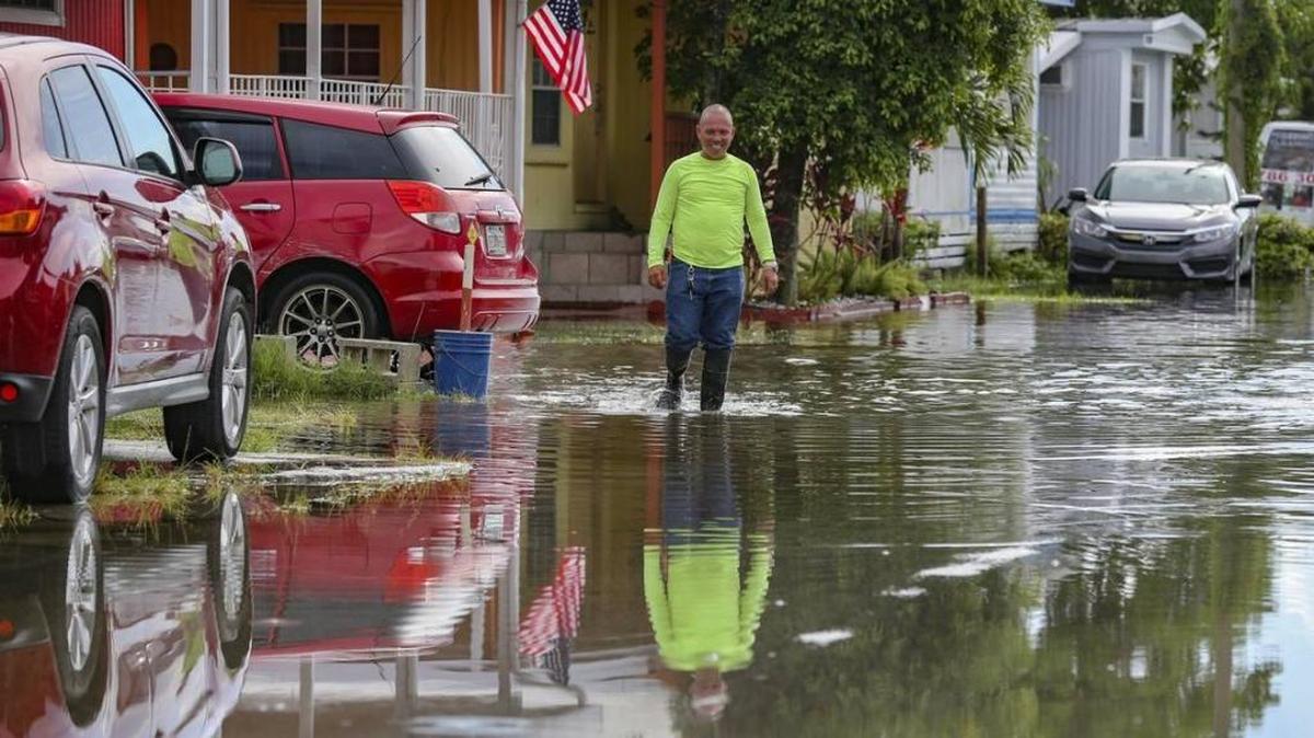 Water everywhere. Robert Gutierrez wears a pair of boots as he walks through a flooded street at Li’l Abner Mobile Home Park in Sweetwater on Tuesday.