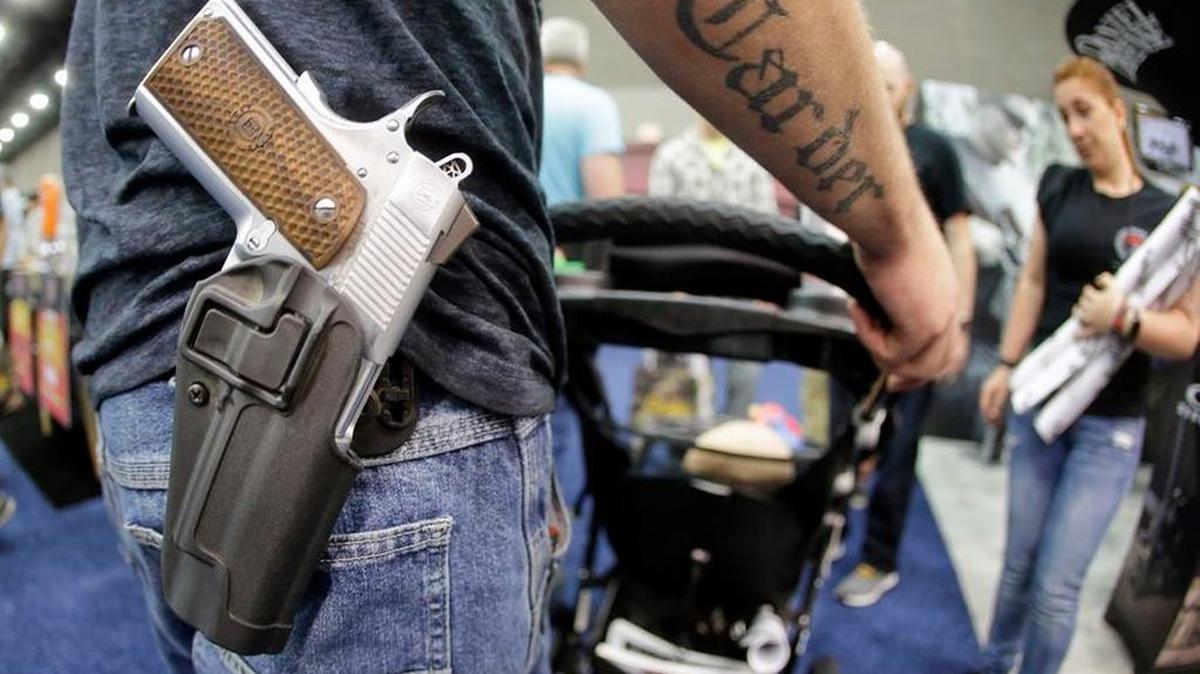 A man wears his handgun in a holster as he pushes his son in a stroller at the National Rifle Association Convention in 2016.