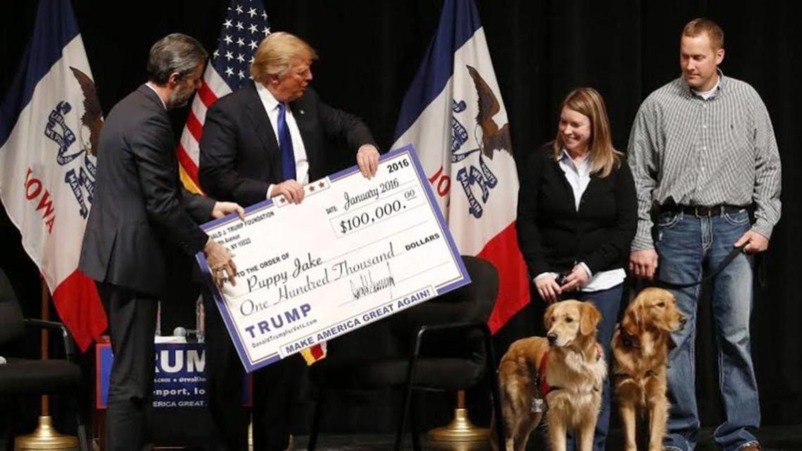Donald Trump presents a check to a service-dog charity, the first disbursement of $6 million he says he raised in Iowa.