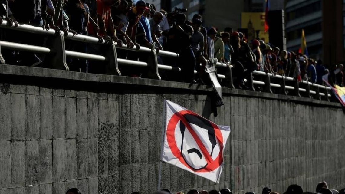 A demonstrator waves a flag in Caracas with the the crossed-out image of Venezuelan President Nicolás Maduro.