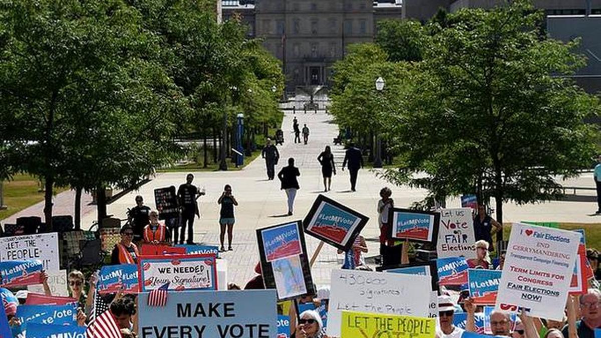 With the Capitol rotunda in the background, demonstrators rally outside the Michigan Hall of Justice in Lansing, Mich., on Wednesday, July 18, 2018, where the Michigan Supreme Court heard arguments about whether voters in November should be able to pass a constitutional amendment that would change how the state’s voting maps are drawn or whether such changes could only be adopted at a rarely held constitutional convention. (Dale G. Young/Detroit News via AP)
