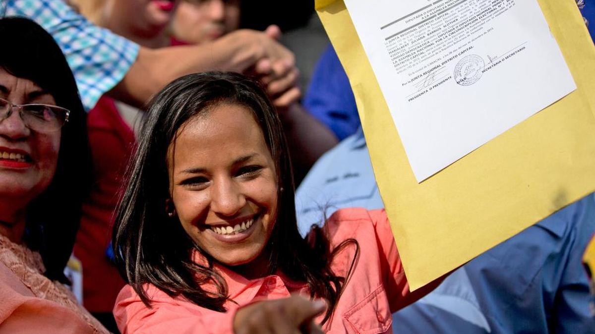 Opposition congresswoman Marialbert Barrios holds up her credentials after receiving them from the Electoral Council.
