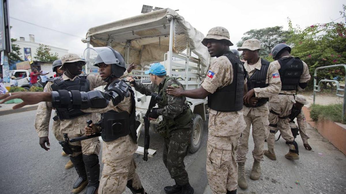 A U.N. peacekeeper takes cover behind soldiers during a protest against Haiti’s electoral council in Port-au-Prince last week.