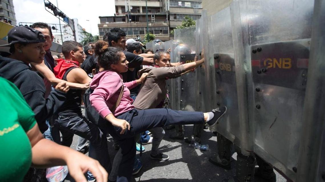 A woman kicks the shield of a National Guard soldier during a protest demanding food in Caracas last week.