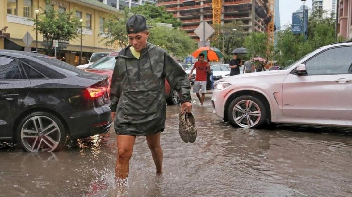 Pedestrians make their way through the flooded streets of 900 block of South Miami Avenue in Brickell area on Tuesday.