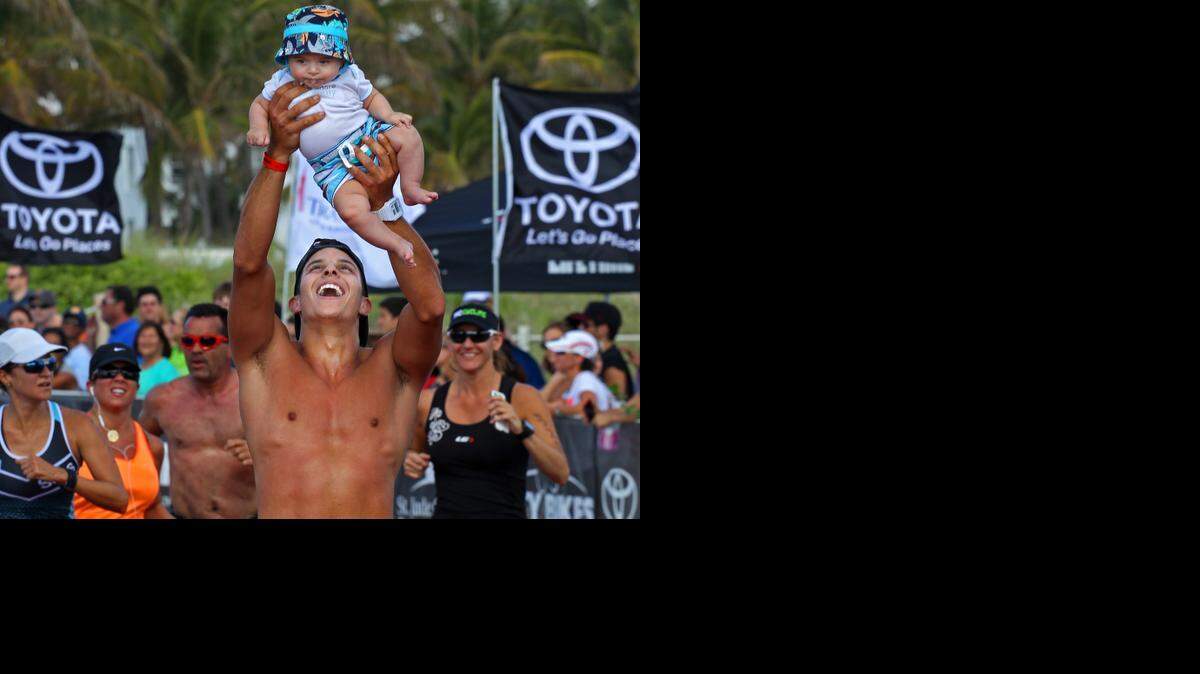 
CARL JUSTE: “Winning Is Not Everything” — Orlando resident Mohannad Abuzant, 24, lifts his 5 month-old son, Mazem, as he and other tri-athletes cross the finish line. About 2,500 athletes participated in 2014 Life Time South Beach Triathlon as they swam, biked and ran through the sun and sand of South Beach on April 6. The race helped raise funds to support St. Jude Children’s Research Hospital. Victory is not always measured in terms of 1st Place, but in remembering the reason you competed in the first place. It was amazing how that thought transformed visually.
