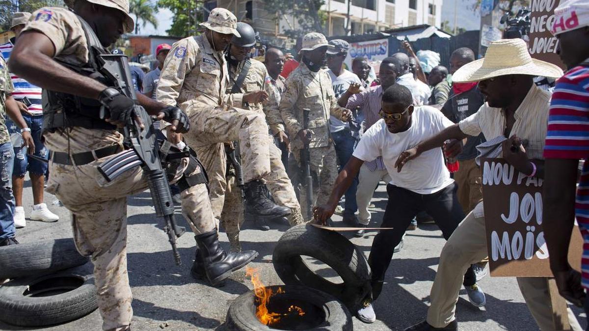 Police try to remove burning tires during a protest by supporters of candidate Jovenel Moïse.