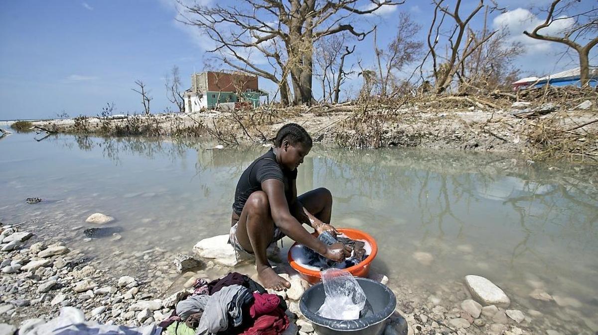 After Hurricane Matthew, Natalie Joseph cleans clothes in a river cutting through Roche a Bateau, Haiti.