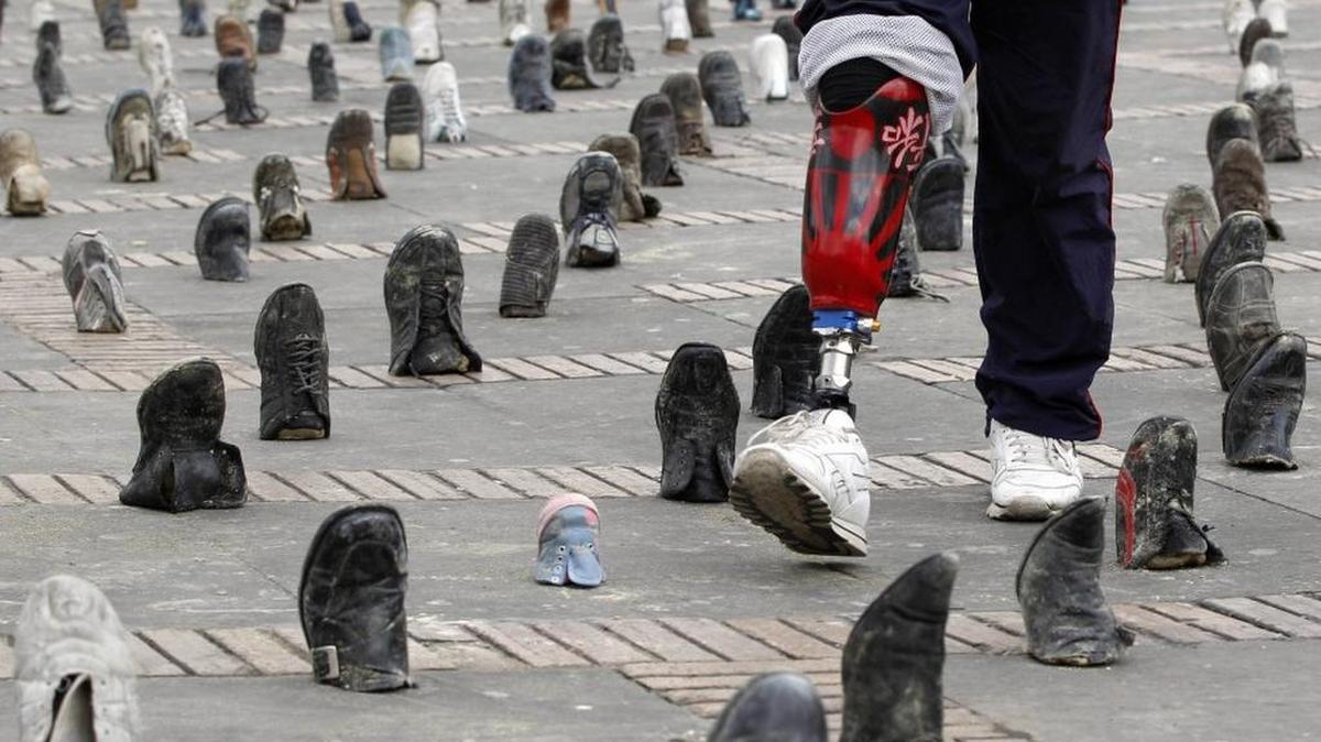 A Colombian amputee soldier, victim of a land mine, walks through a shoe installation marking International Day for Landmine Awareness in Bogota.