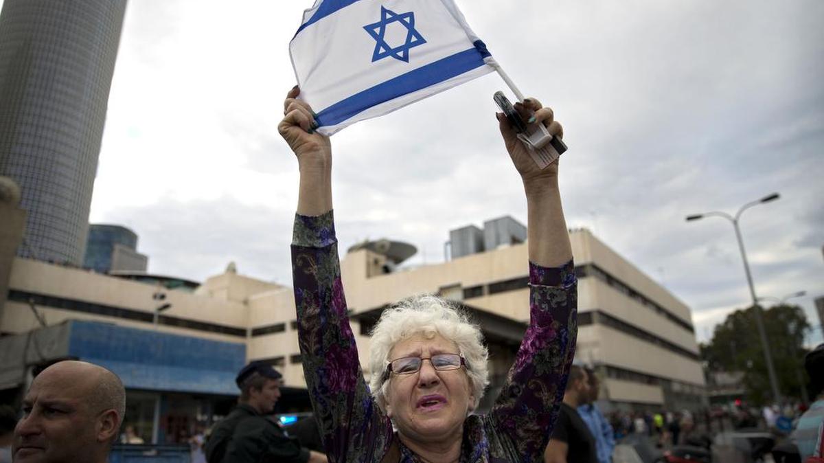 An Israeli woman holds a flag at the scene of an Oct. 7 stabbing by an Arab attacker in Tel Aviv.