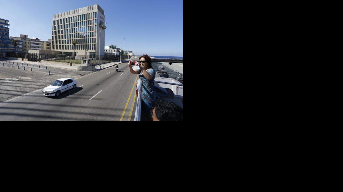 
TOURISM: A tourist atop a sightseeing bus snaps photos as it passes the U.S. Interests Section building in Havana. U.S. tourism is expected to increase with the renewal of full U.S.-Cuba diplomatic ties.
