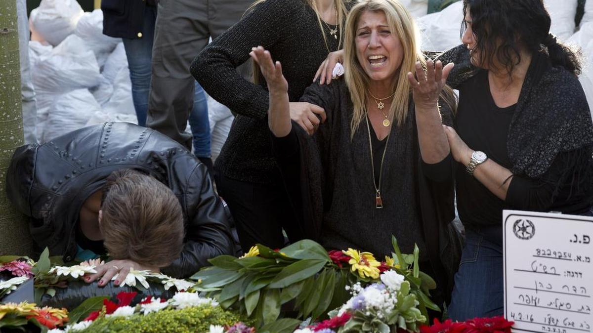 Mourners cry over the grave of Hadar Cohen, an Israeli police officer killed this week after three Palestinians killed an Israeli security officer and wounded another in Jerusalem.