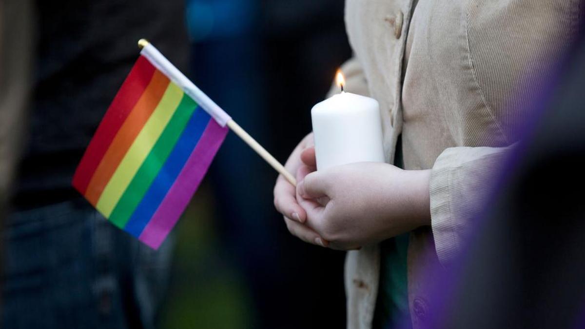 A woman holds a candle and a pride flag during a vigil for the Orlando shooting victims.