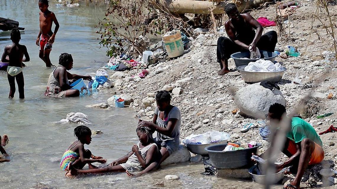 People bathe and clean clothes in a river cutting through Roche a Bateau, Haiti, after the devastation caused by Hurricane Matthew.