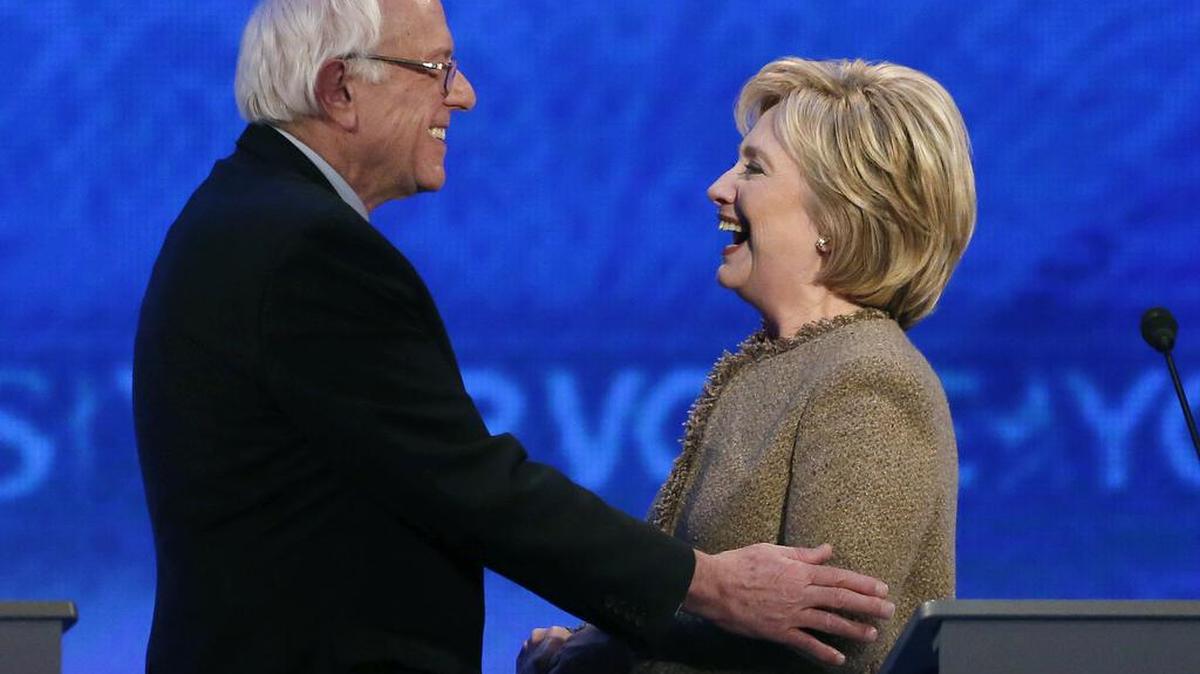 Bernie Sanders, left, and Hillary Clinton share a laugh during a break at the Democratic presidential debate on Saturday.