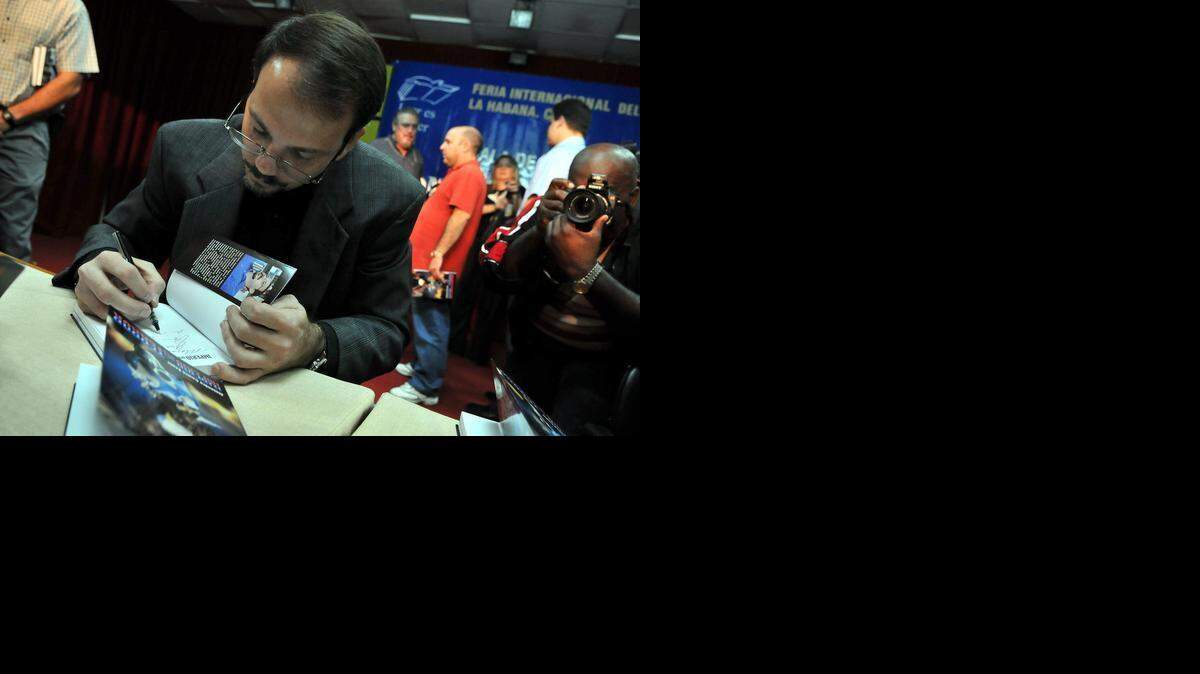 
AUTHOR: Alejandro Castro Espín, son of Raúl Castro, signs a copy of his book, “Imperio del Terror,” during a book fair in Havana in 2009.
