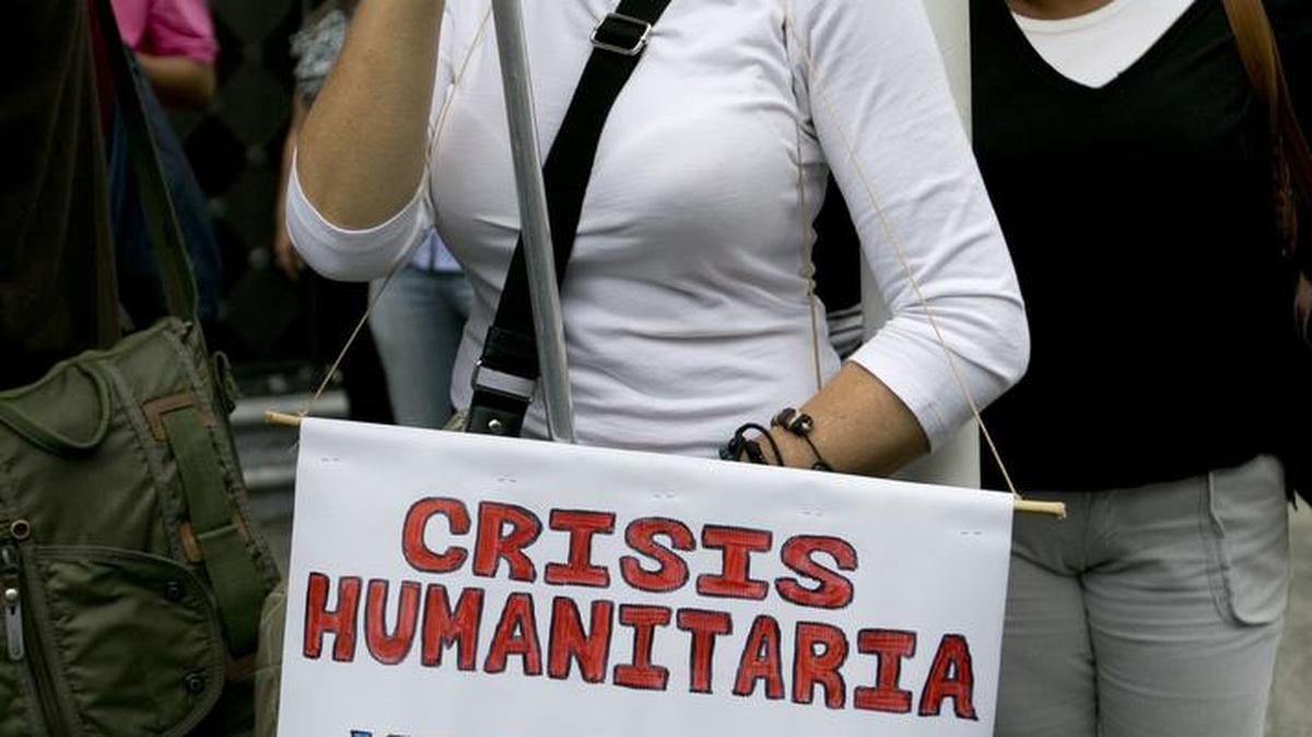 An anti-government protestor in Caracas holds a sign that reads, “Humanitarian crisis, Venezuela dies, SOS.” Critics say the government is openly violating the Constitution.