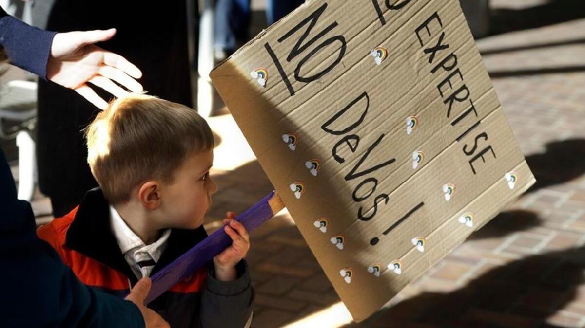 At a rally in Portland, Oregon, a young child carries a sign critical of Betsy DeVos, who was confirmed as education secretary.