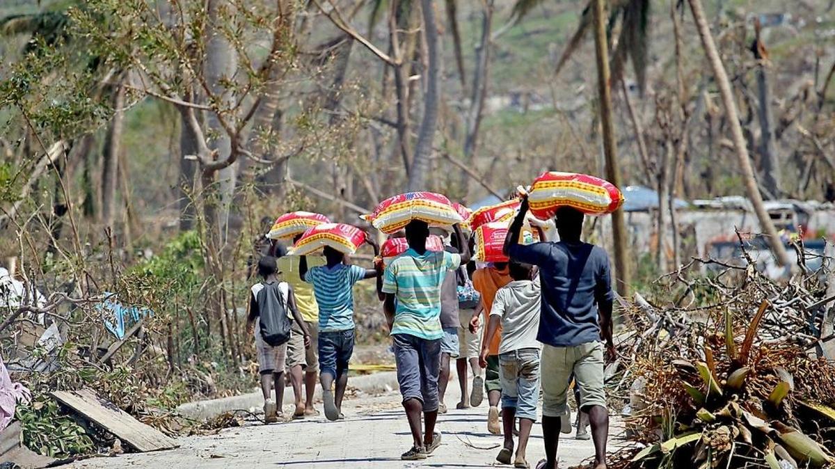 After Hurricane Matthew, young men carry bags of rice they got from a food distribution center near Port Salut, Haiti.