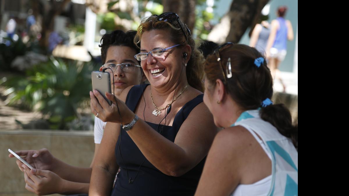 
HAVANA HOTSPOT: Laura Martinez, flanked by her nephew Nelson Suarez, left, and friend Ana Maria Beltran, communicates with a son in Canada using the first public Wi-Fi hotspot in Havana shortly after it became available.
