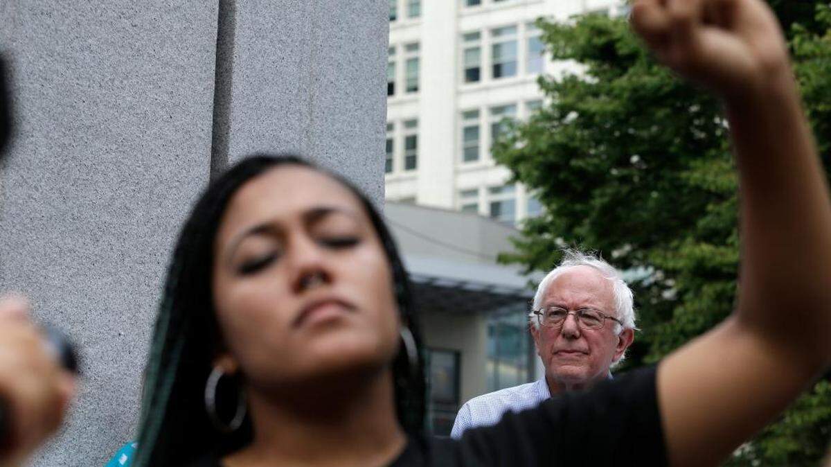Mara Jacqueline Willaford, a Black Lives Matter advocate, holds her fist overhead at a rally for Democratic presidential candidate Sen. Bernie Sanders, I-Vt., standing nearby.