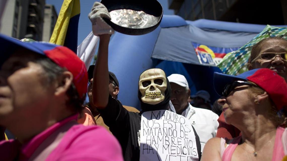 A Venezuelan protestor wears a sign that reads in Spanish: “Maduro you are starving us to death, there are no medicines, leave, now.”