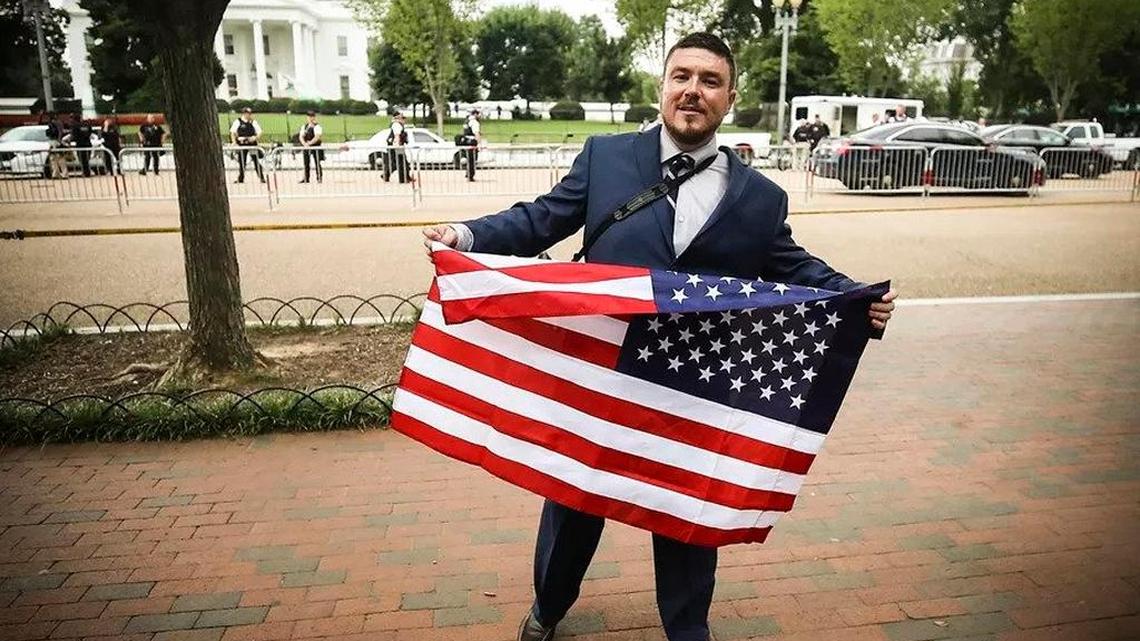 Jason Kessler, who organized the sparsely attended Unite the Right 2 rally for white supremacists in Washington, D.C., displays an American flag.