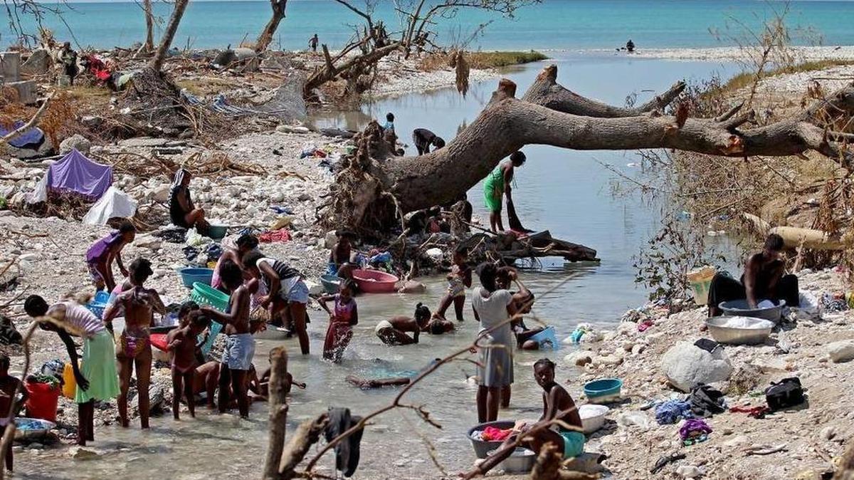 Women left destitute after Hurricane Matthew bathe and clean clothes in a river cutting through Roche-a-Bateau.
