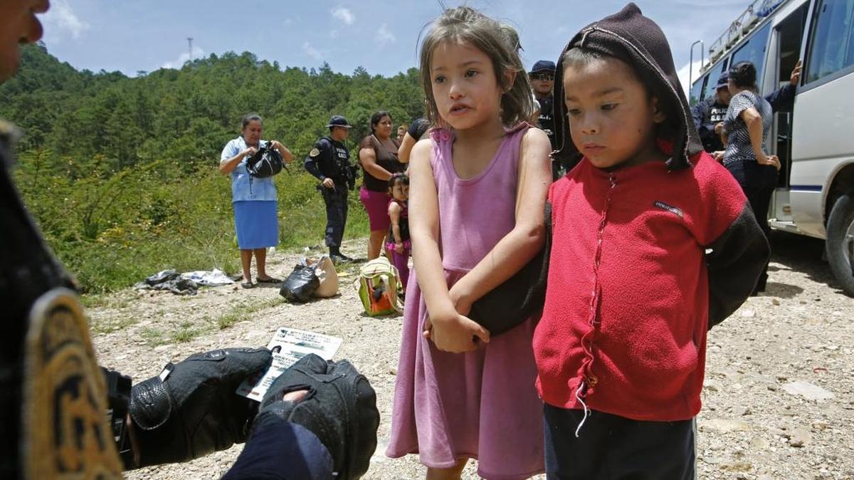 Two children on a road in Honduras are questioned by police to find out if they are victims of people smuggling to the U.S.