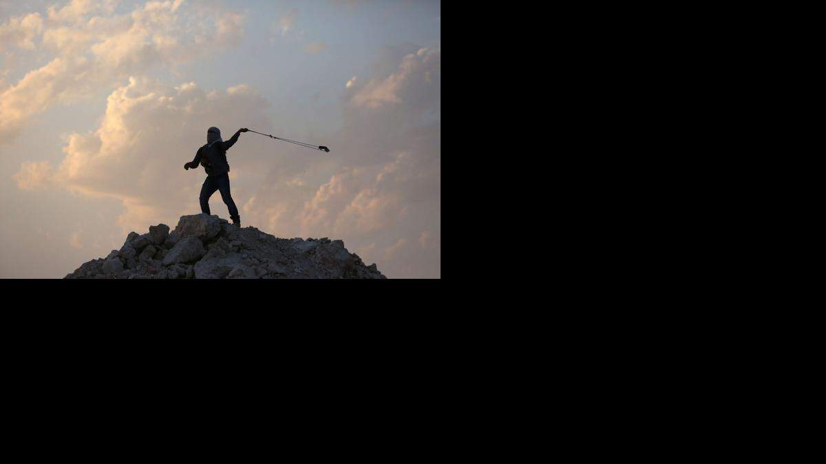 
WEST BANK: A Palestinian protester uses a sling shot to throw a rock at Israeli security forces during a protest near Ramallah. 
