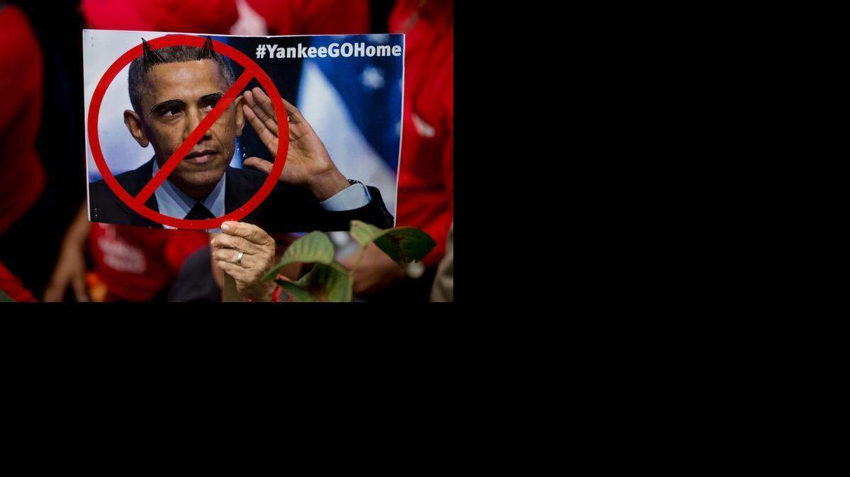 
CARACAS: A government supporter holds a poster showing a defaced photograph of U.S. President Barack Obama during a rally outside Miraflores presidential palace in Caracas on Sunday.
