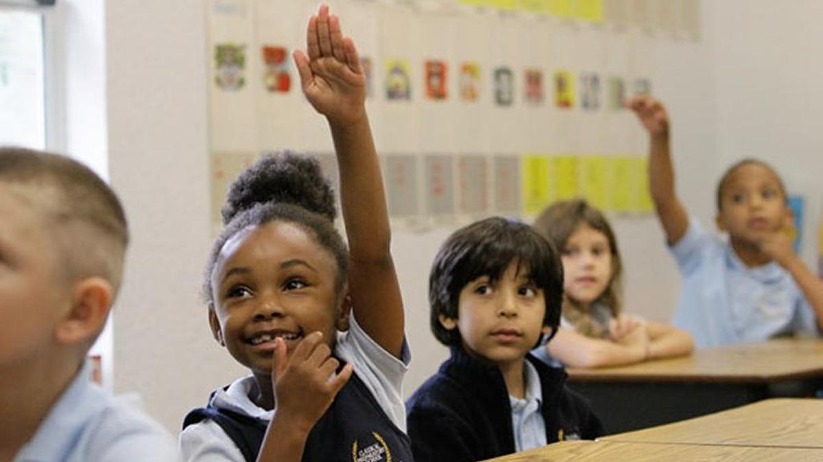 A student raises her hand with the answer to a question at a Pasco County charter school.