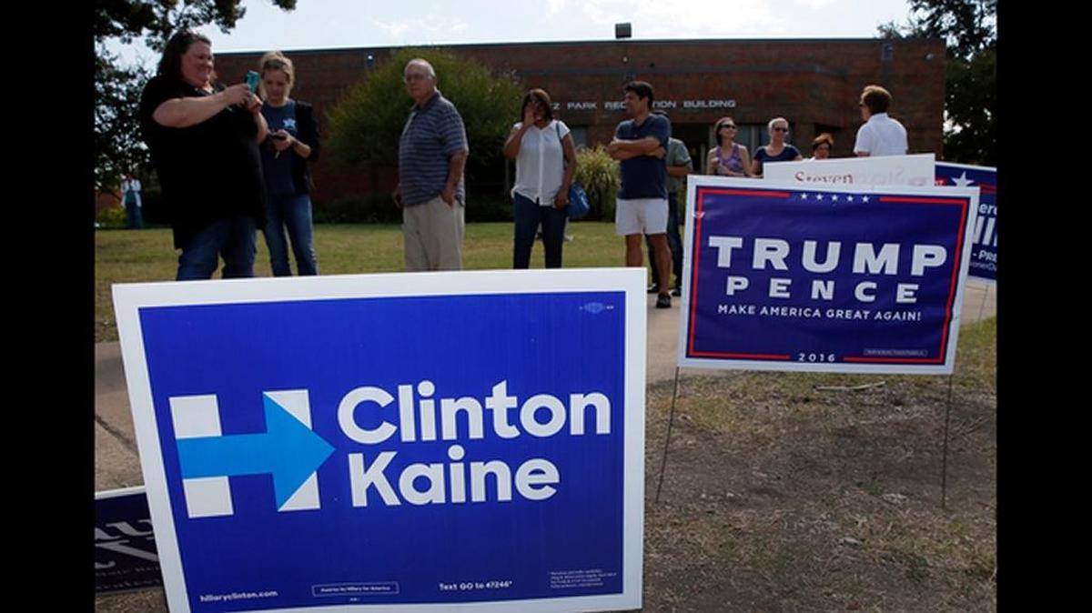 Early voters line up by campaign signs in Dallas.