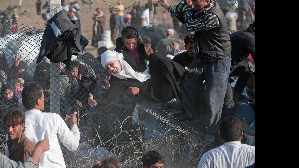 
DESPERATION: Refugees break down a border fence and cross into Turkey from Syria as part of the mass displacement of people due to the Syrian war.
