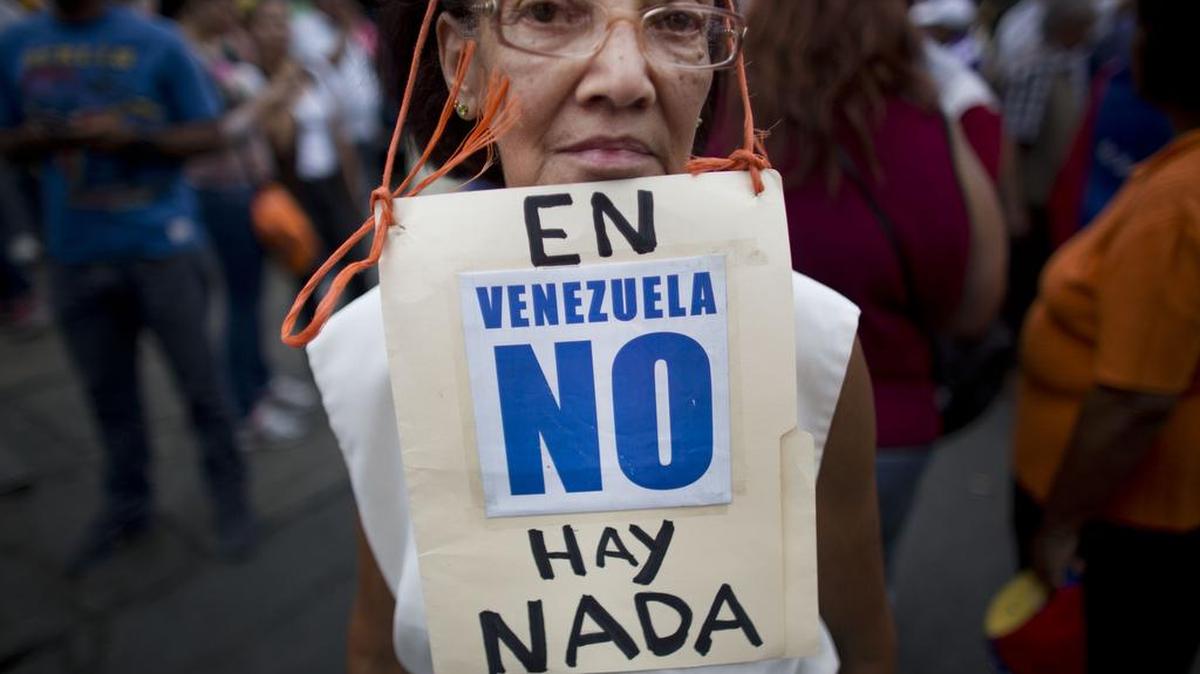 Woman protesting shortage of consumer goods in Venezuela wears a sign that reads in Spanish: “In Venezuela, there’s nothing.”
