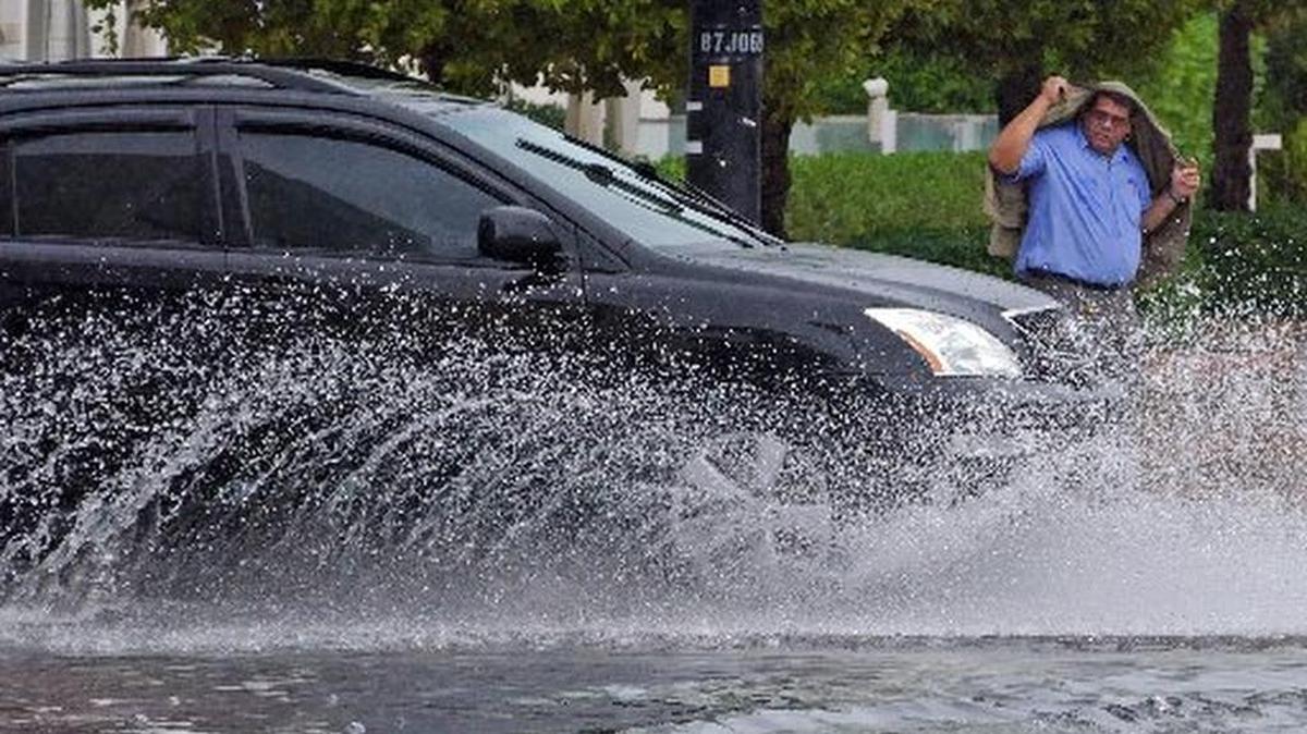 A pedestrian tries to stay dry while crossing Collins Ave. at 22nd Street after rain in February.