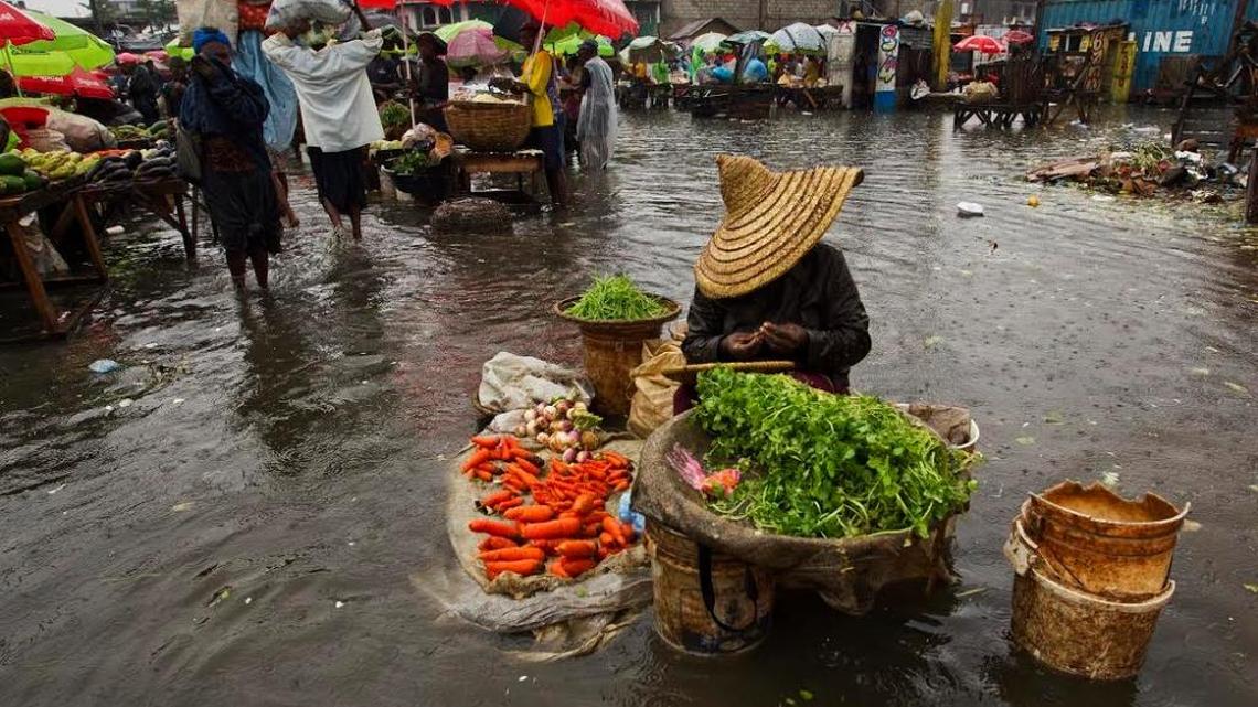 A woman sells produce at a flooded marketplace in Haiti.