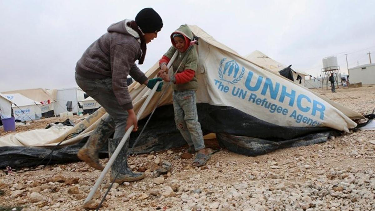 
HOME, FOR NOW: Syrian children, refugees at the Zaatari camp in Jordan, put up their tent after a storm.
