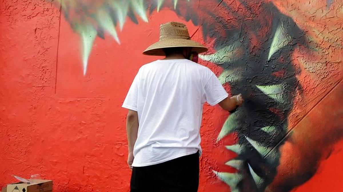 An artist paints a piece, Wynwood Shark, on a wall in Wynwood in preparation for Miami Art Week.