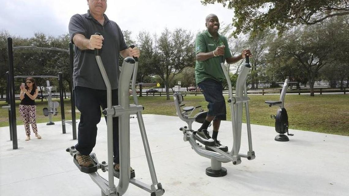 David Livingstone, left, and Mitch Burroughs, employees of Miami-Dade’s parks department, use the elliptical machines at Miami-Dade Parks' new Fitness ZoneAE outdoor gym in Aventura.