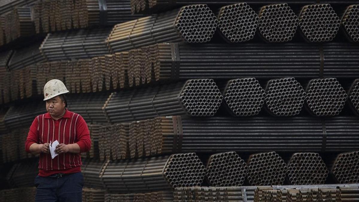 A steel worker walks past steel rods at a plant in Tangshan, Hebei province, China.