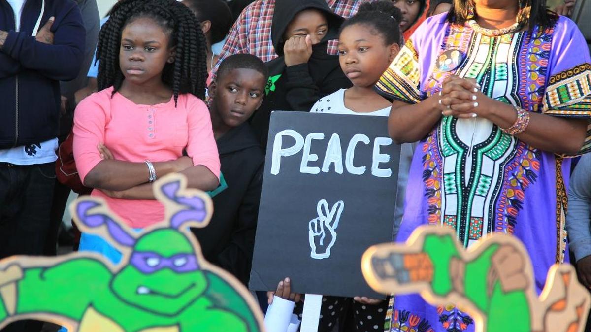 A sign’s message, and plea, reflects the wishes of communities under siege from deadly violence.