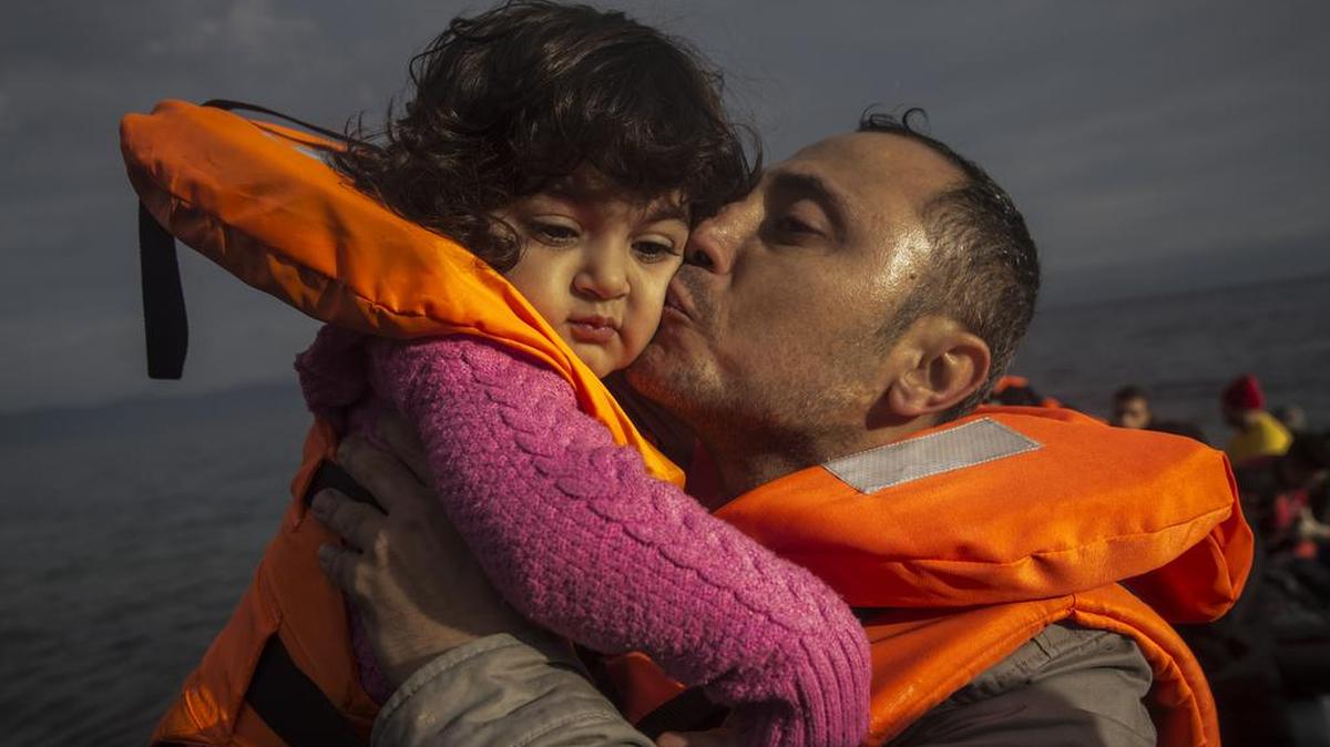 A migrant kisses his child on a beach on the Greek island of Lesbos after crossing the Aegean sea in a dinghy.